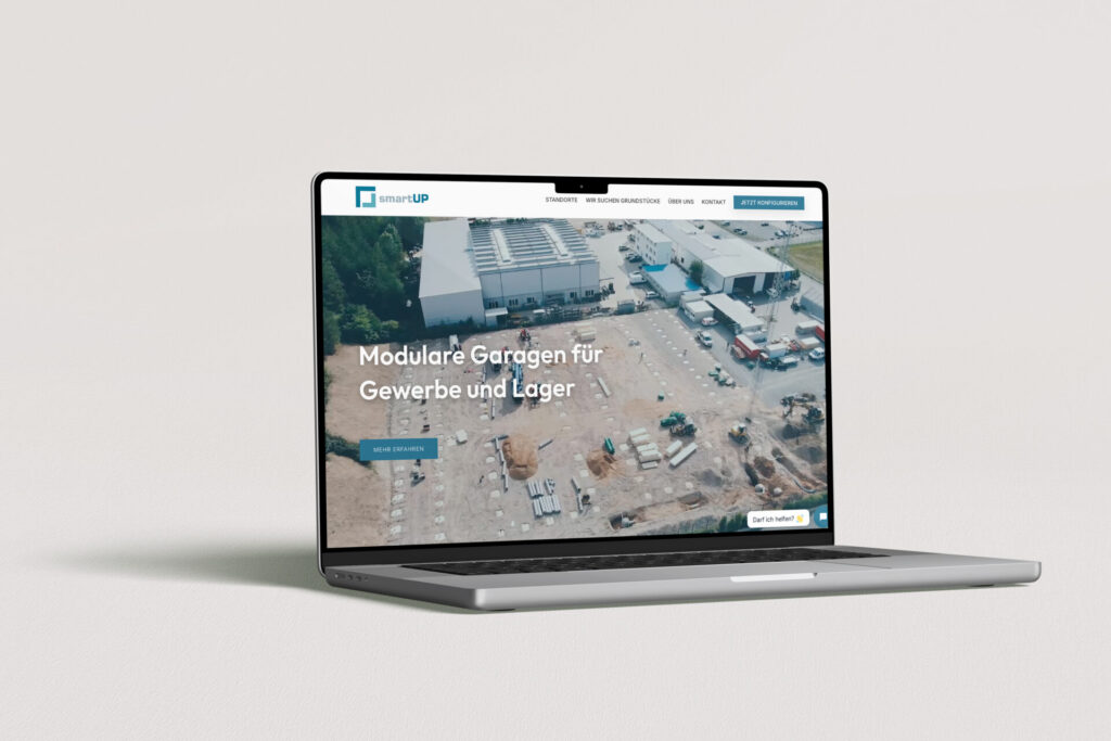 website-relaunch-smartUP-immobilien-gmbh Laptop mit geöffneter Website, die modulare Lösungen für Gewerbe und Industrie zeigt, auf einem Baustellenareal.