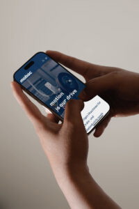Person hält ein Smartphone in der Hand, auf dem eine Website sichtbar ist, die moderne Design-Elemente zeigt.