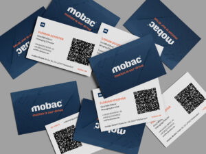 Visitenkarten von mobac GmbH mit dem Namen Florian Schiffer, Geschäftsführer. Die Karten sind in einem modernen Design mit einem QR-Code und den Kontaktdaten, darunter Telefonnummer und E-Mail-Adresse, angeordnet. Das Logo und der Slogan „motion is our drive“ sind prominent sichtbar.