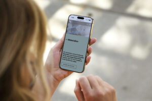 Person, die ein Smartphone in der Hand hält und eine mobile Webseite mit einem Textinhalt betrachtet. Helle Umgebung mit unscharfem Hintergrund.