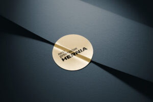 Goldene Plakette mit dem Schriftzug "HERNIA" auf dunklem Hintergrund, ideal für medizinische oder gesundheitliche Themen.