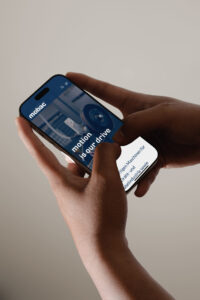 Person hält ein Smartphone mit der Website von Mobac, die Maschinen für die Draht- und Kabelindustrie präsentiert.