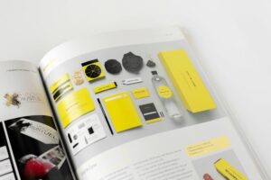 Designbeispiel für Branding und Verpackung mit gelben Akzenten, einschließlich Flasche, Notizblöcken und Visitenkarten, präsentiert in einem Magazin.