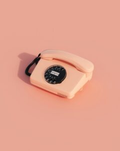 Vintage rosa Telefon mit Wählscheibe auf einem einfarbigen Hintergrund.